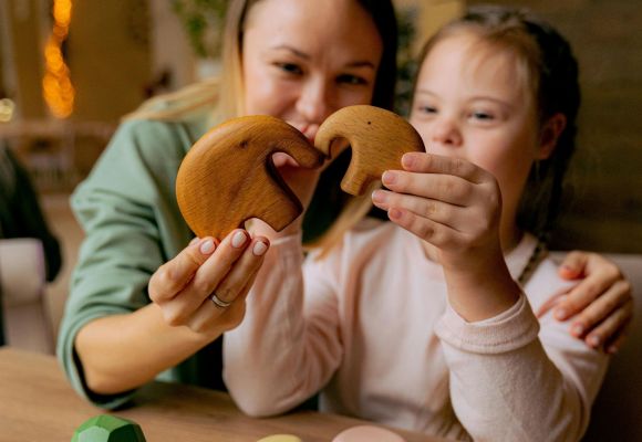 Mutter und Tochter formen Herz mit Holzfiguren