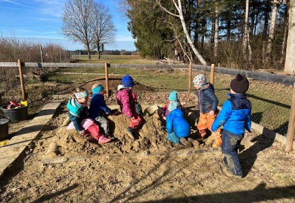 Warm eingepackte Kinder im Sandkasten