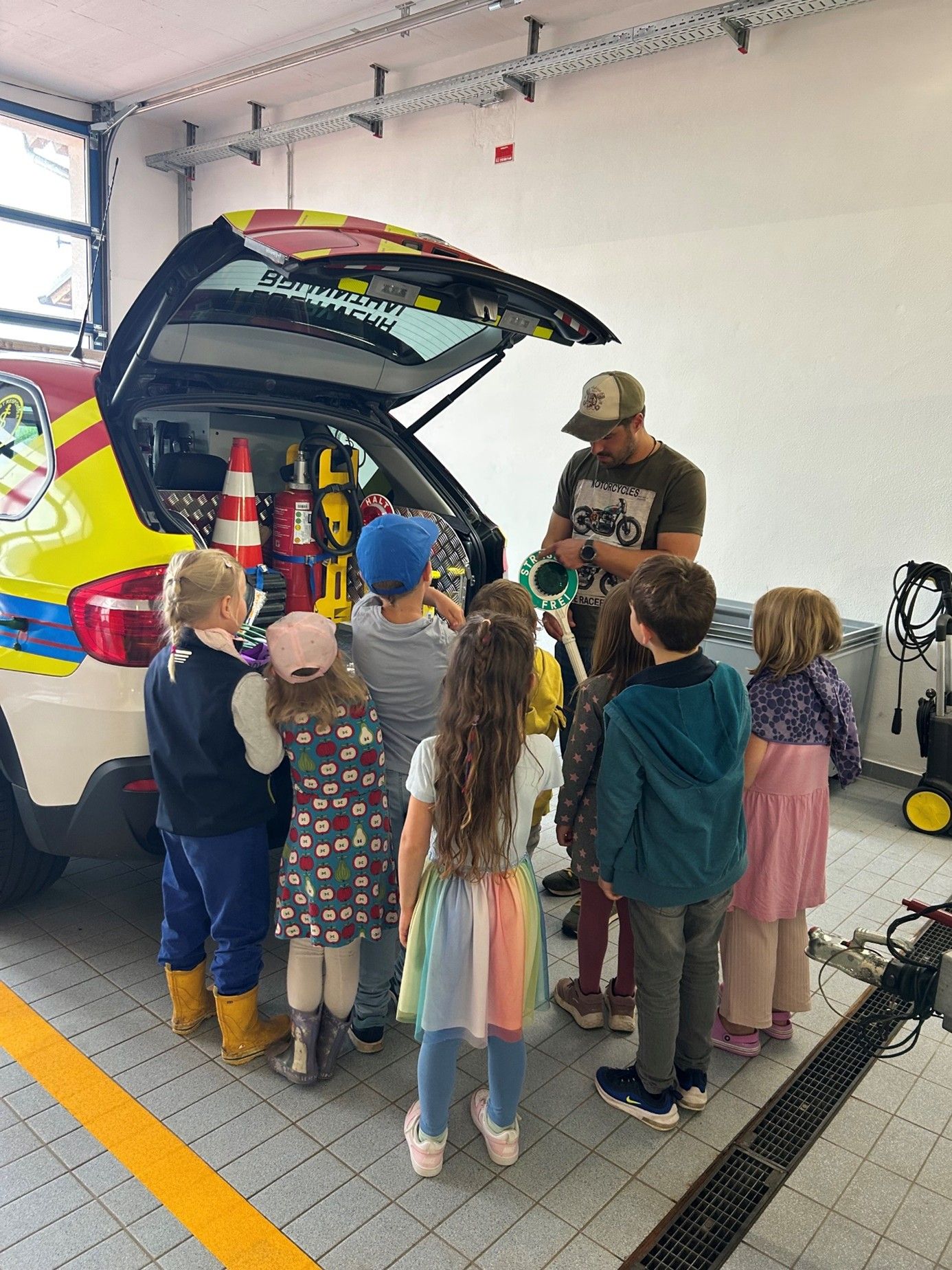 Kinder und Feuerwehr-Mitarbeiter an Einsatz-Auto