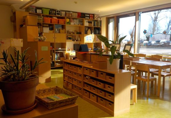 Innenraum des Hortes mit Materialschrank, Tischen und Stühlen