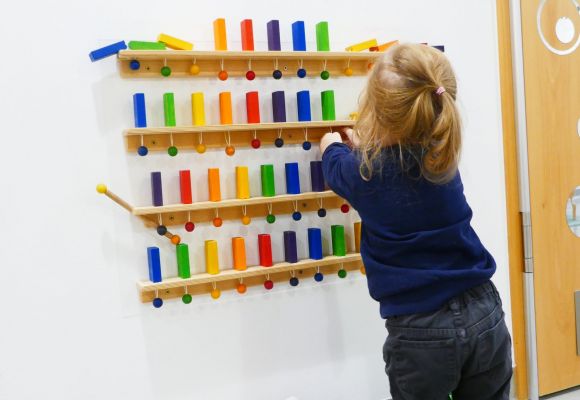 Kleinkind an Spielwand