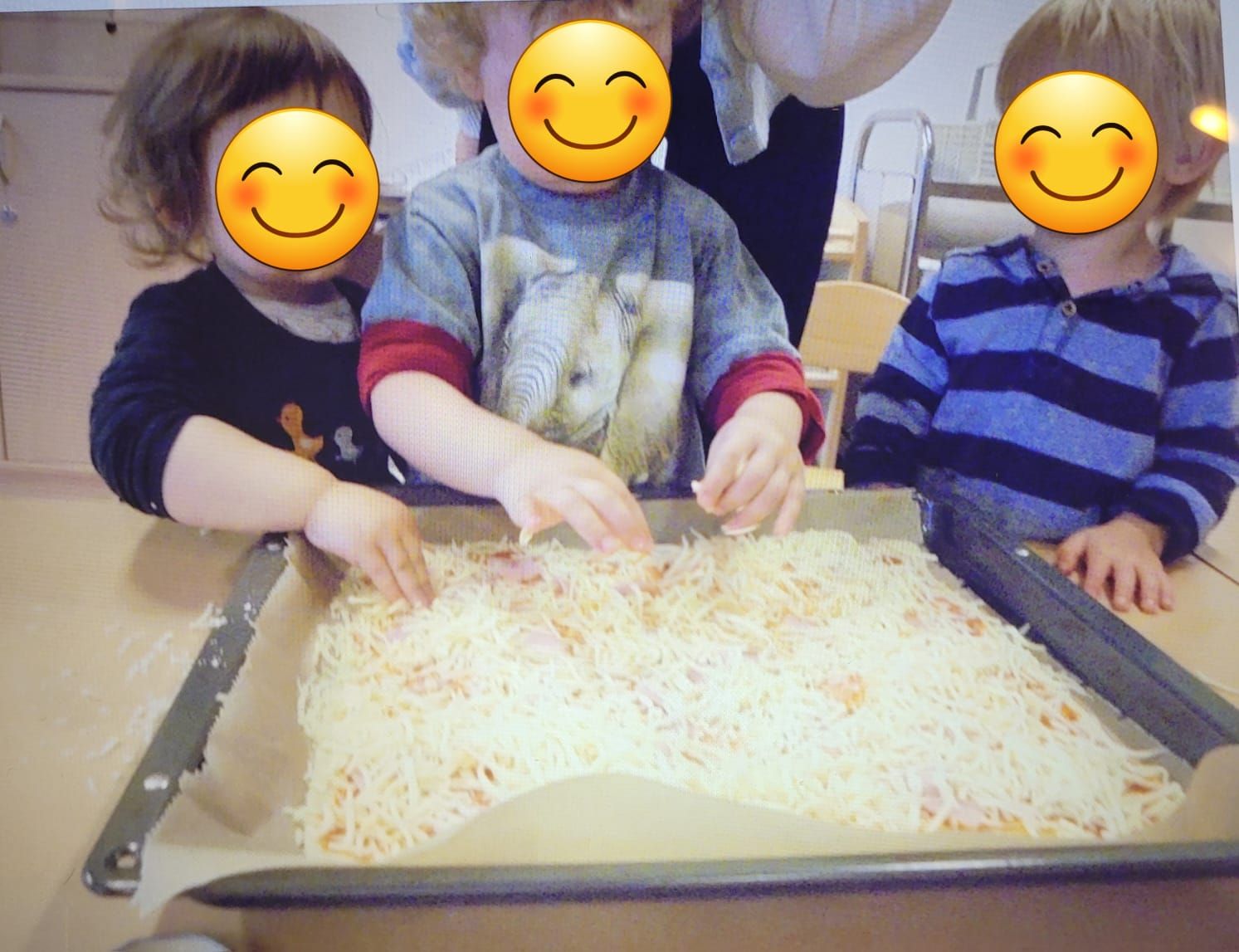 Kinder belegen ein Blech Pizza