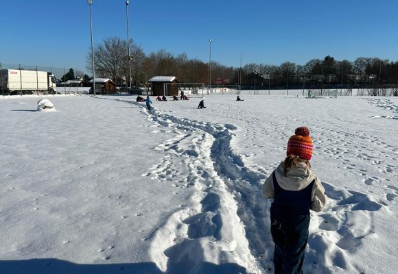 Kind von hinten mit Pudelmütze im Schnee