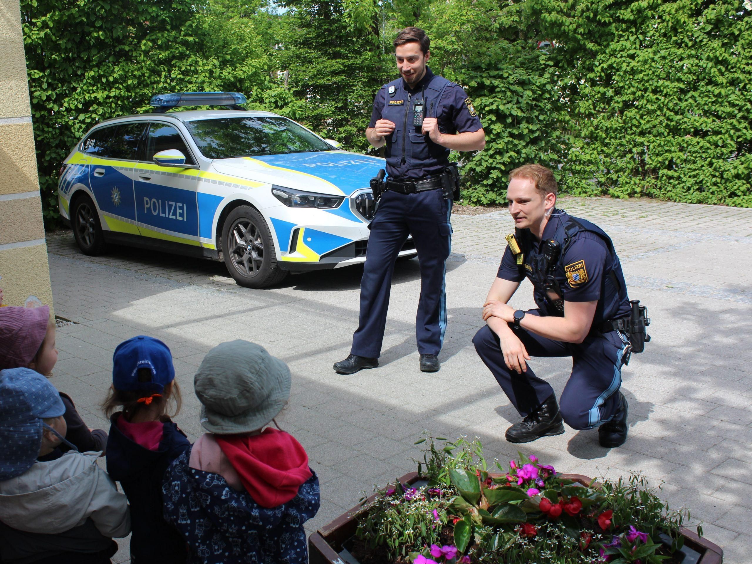 Kindergruppe mit zwei Polizisten und Polizeiauto