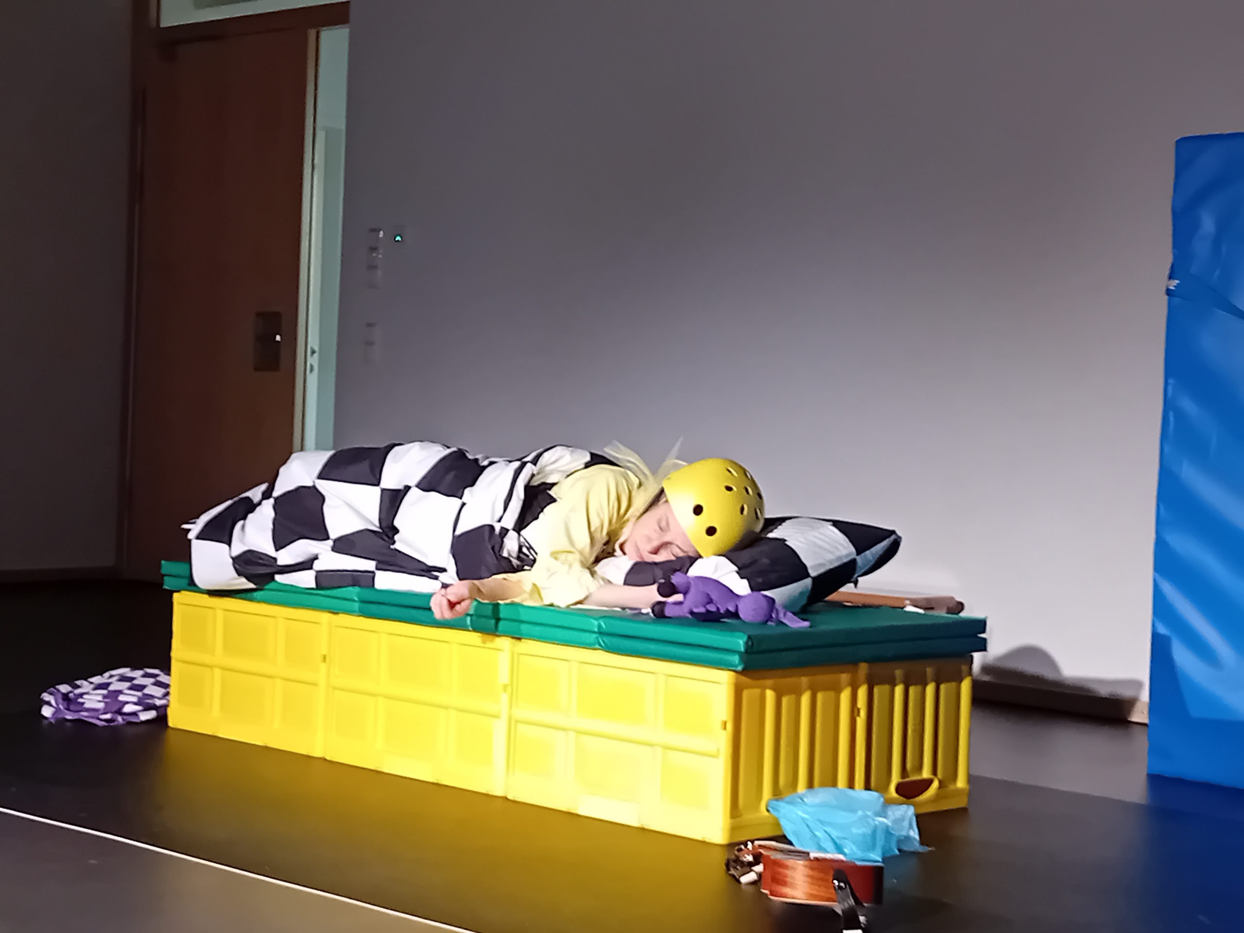 Theaterszene: Schlafende Frau mit Fahrradhelm