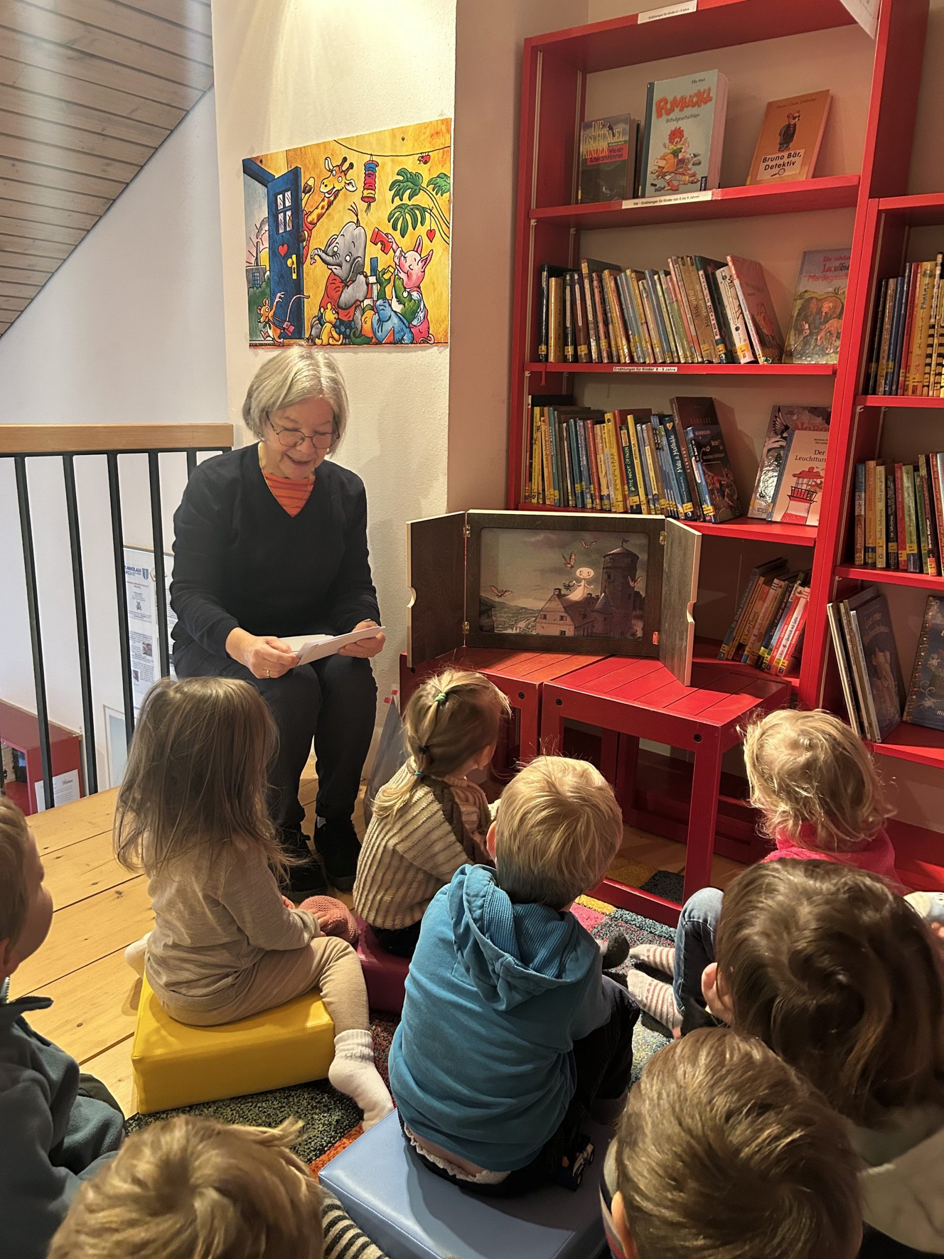 Kinder in der Bücherei mit Karin Döhnel, die ein Buch vorliest
