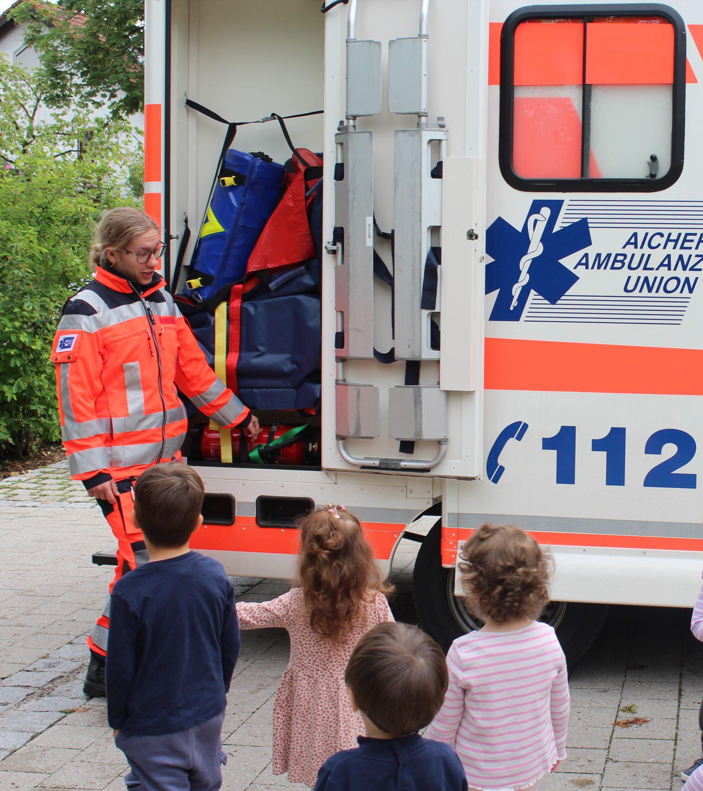 Kinder an Ambulanzauto mit Sanitäter