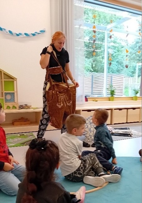 Erzieherin zeigt Kindern eine Lederhose