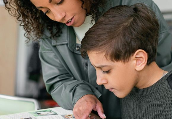 Lehrerin zeigt einem Jungen etwas im Buch