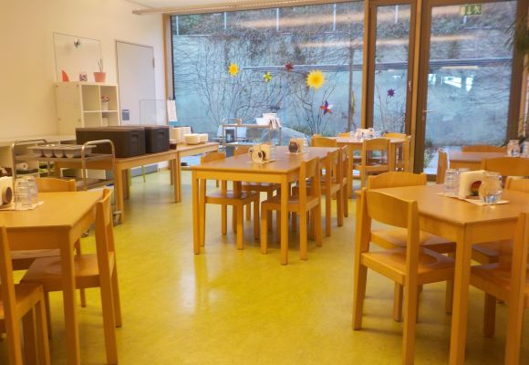 Innenraum des Hortes mit Tischen und Stühlen