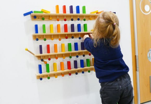 Kleinkind an Spielwand