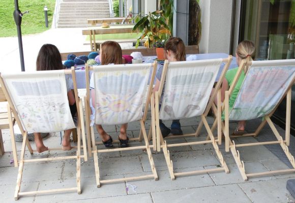 Vier Kinder von hinten in Liegestühlen beim Basteln mit Wolle