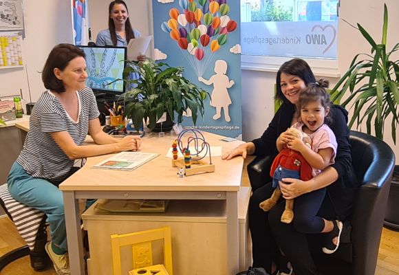 Zwei Frauen am Tisch im Gespräch, eine mit Kind auf dem Schoß